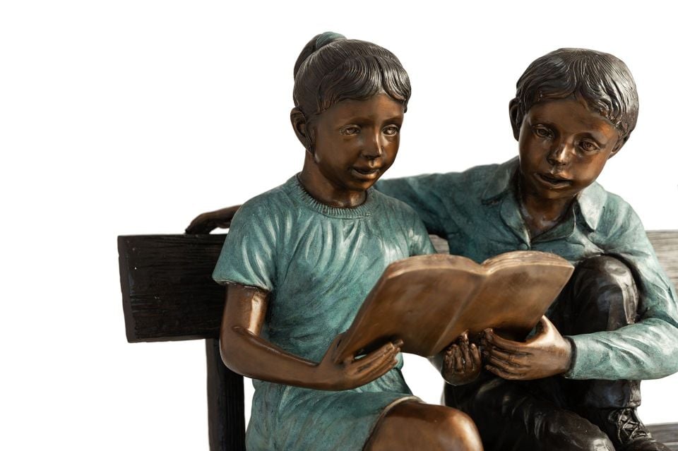 BOY AND GIRL READING A BOOK ON A BENCH